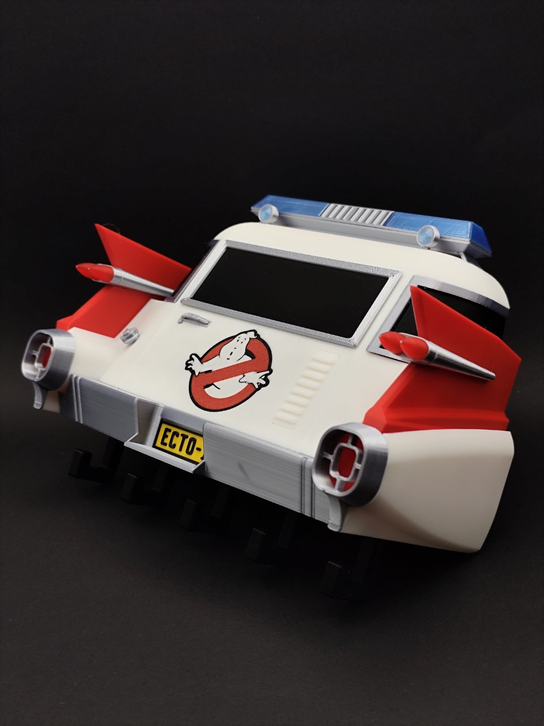 Angled front view of Ghostbusters Ecto-1 3D printed key holder on black background