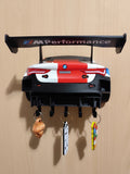 M4 GT3 key hanger mounted on a wood wall with five hooks and three keychains