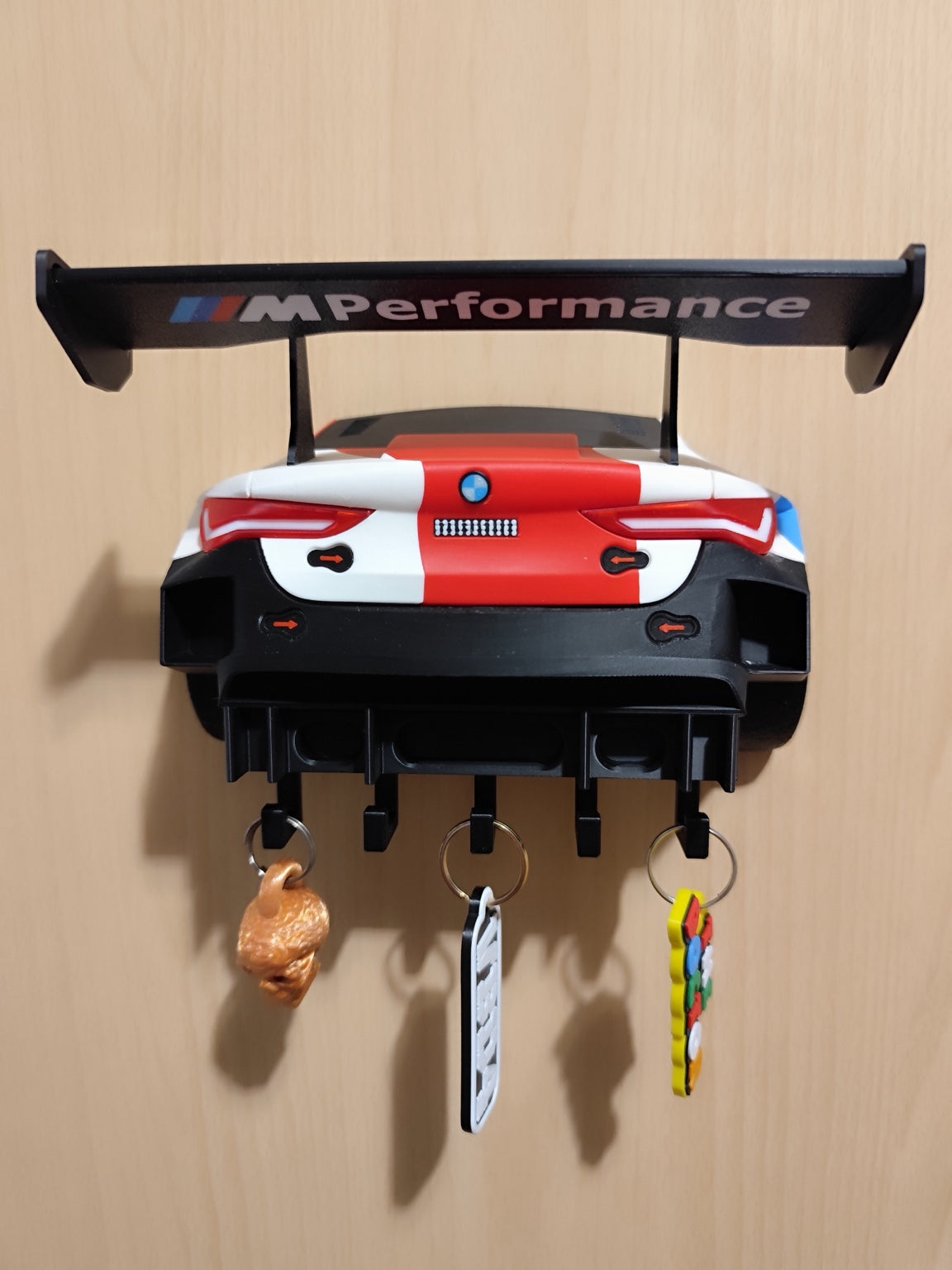 M4 GT3 key hanger mounted on a wood wall with five hooks and three keychains