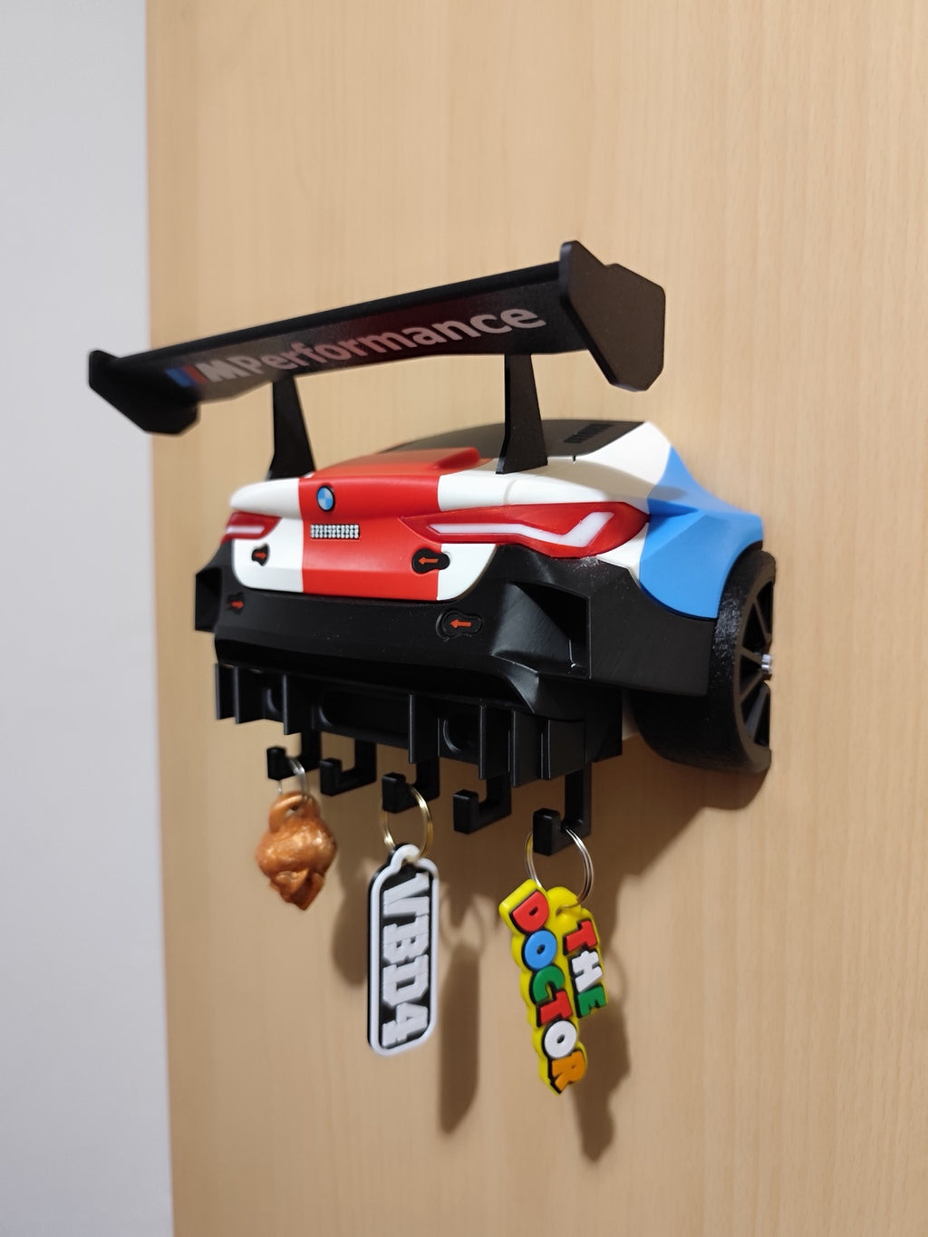 Angled view of the wall-mounted M4 GT3 key holder with red white and blue bodywork